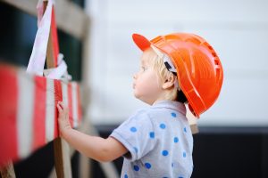 Child in hardhats working outside construction site