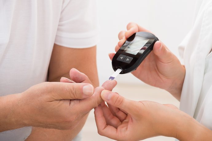 Diabetes Alert Day: Doctor Using Glucometer On Patient's Finger to Measure Blood Sugar Levels